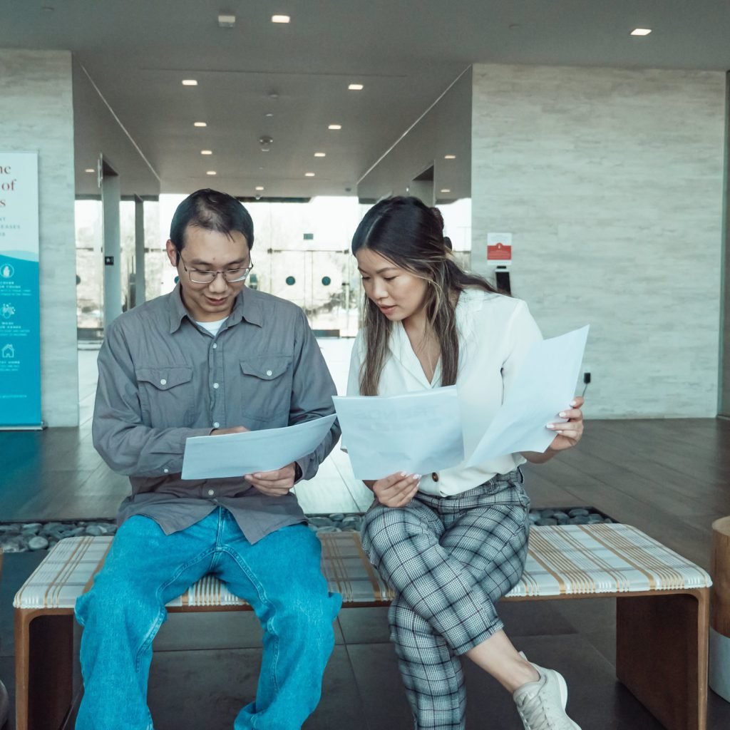 man and woman talking to each other while looking on their papers