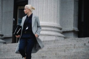 A female immigration lawyer confidently descending the steps of a public building, holding files and folders, illustrating expertise in handling the Affidavit of Support process.