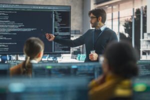 teacher giving computer science lecture to diverse multiethnic group of female and male students in a college room