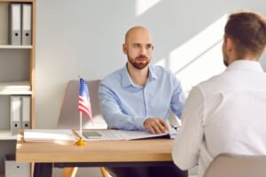 Consul at Consulate of United States of America sitting at office table with American flag