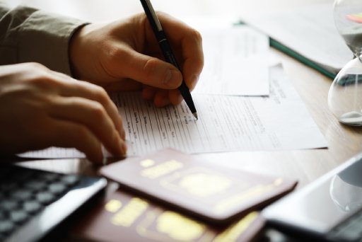 Filling Out Forms for International Travel with Passports, Papers, and Pen on Desk