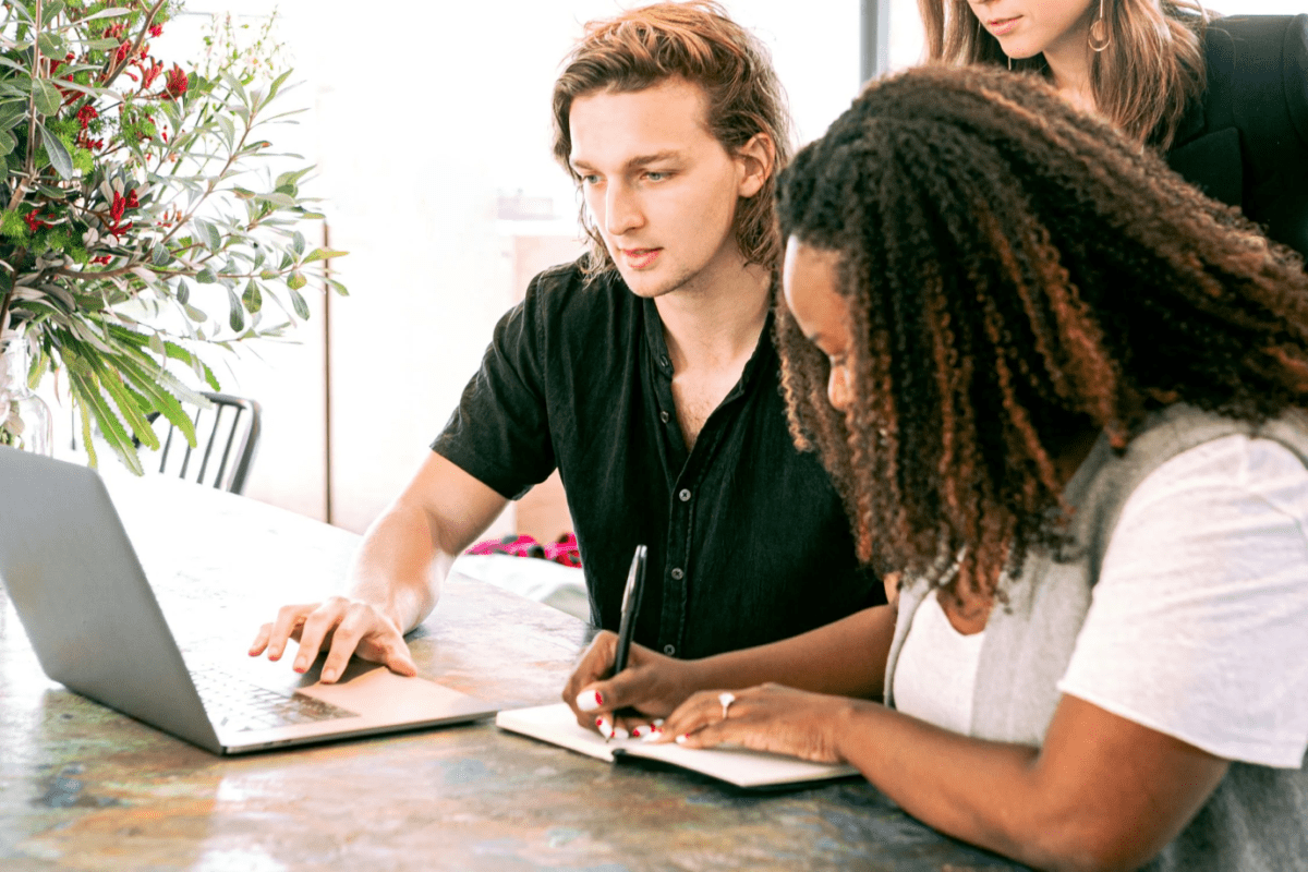 An international graduate reviewing visa application requirements on a laptop, with friends providing support.