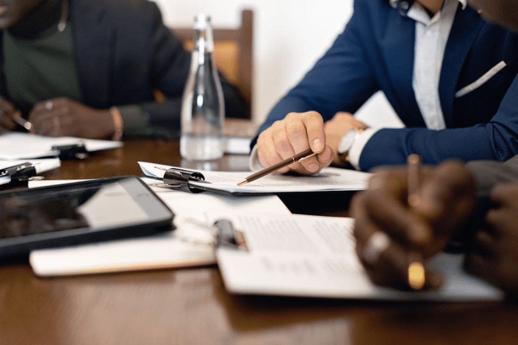 A close-up of professionals reviewing and signing documents during a business meeting.