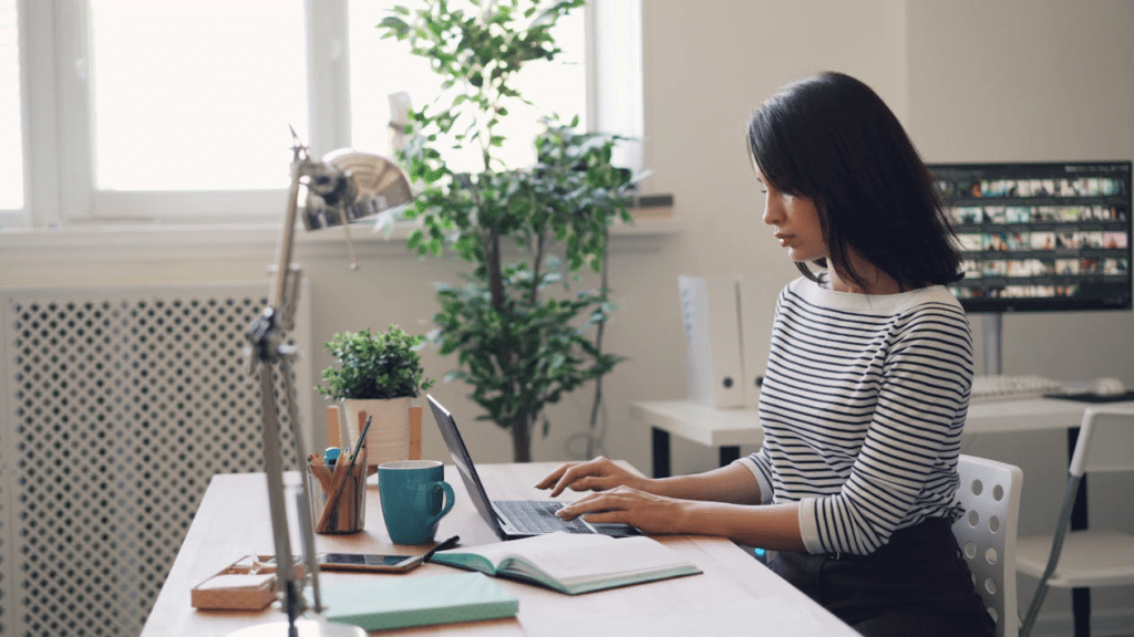 A woman working on her laptop in a modern home office setting.