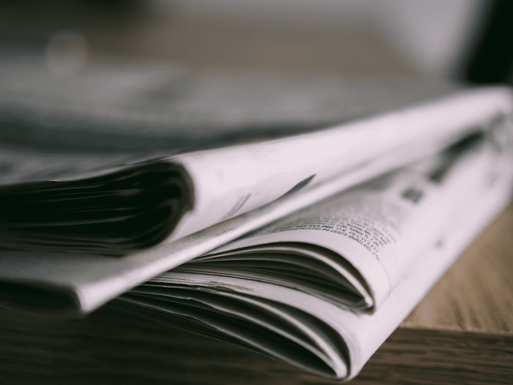 A close-up of stacked newspapers on a wooden surface.