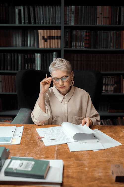 A highly skilled professional reviewing important documents at a desk in a library.